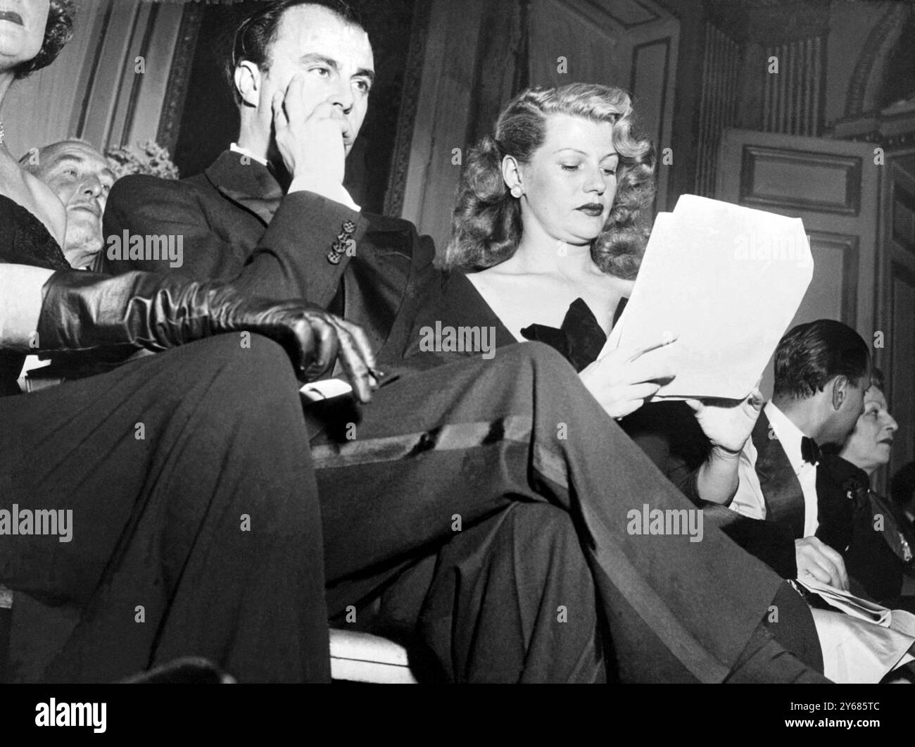 Although Prince Aly Khan, eldest son of the Aga Khan, has not yet obtained his divorce, he and Rita Hayworth, glamorous Hollywood film actress, whom he plans to marry as soon as it is possible, have been buying gowns for her wedding trousseau in Paris. Photo shows Prince Aly and Rita Hayworth during a presentation of spring fashions at Maggy Rouff, Paris.  7th February 1949 Stock Photo