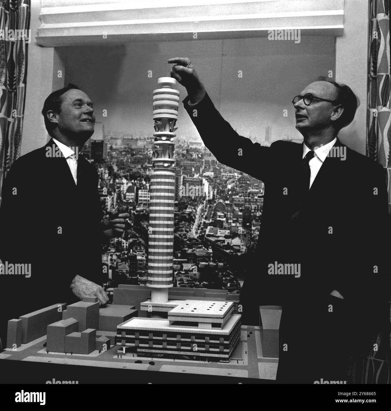 On view in London today was a model of Britain's tallest building which will be completed in 1963. Explaining the details to Mr Richard Thompson, Parliament secretary to the Ministry of Works (left) is the architect Mr Eric Bedford. The tower will rise on a site just off Tottenham Court Road in London, and is to be built by the Ministry of Works for the Post Office. Its main object will be for the transmitting and receiving of micro-waves to link television and telephone services. However, the most novel feature of the tower will be a revolving restaurant at a height of almost 500 ft giving di Stock Photo