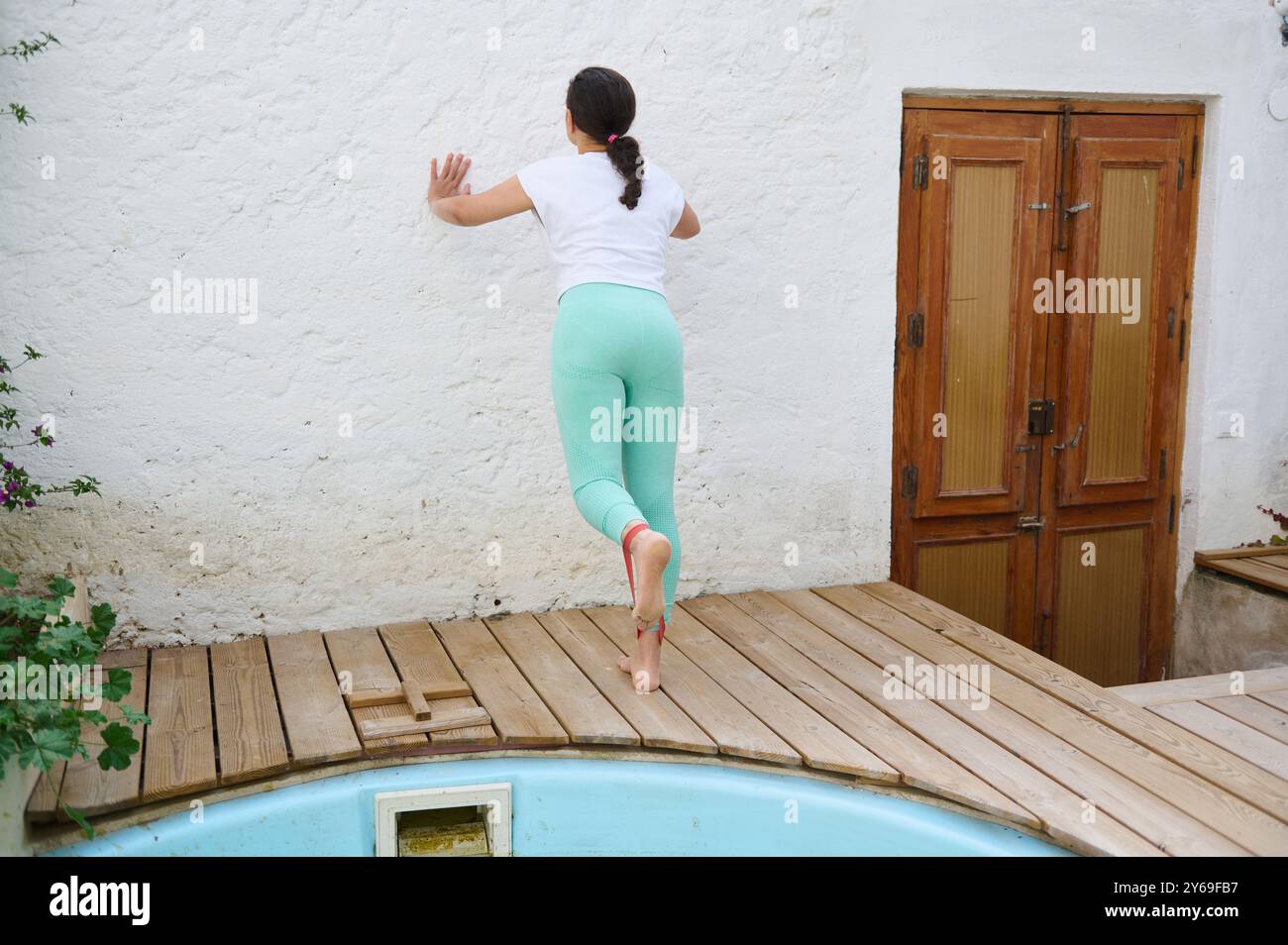 A woman in yoga attire performs a balancing pose outdoors, leaning ...