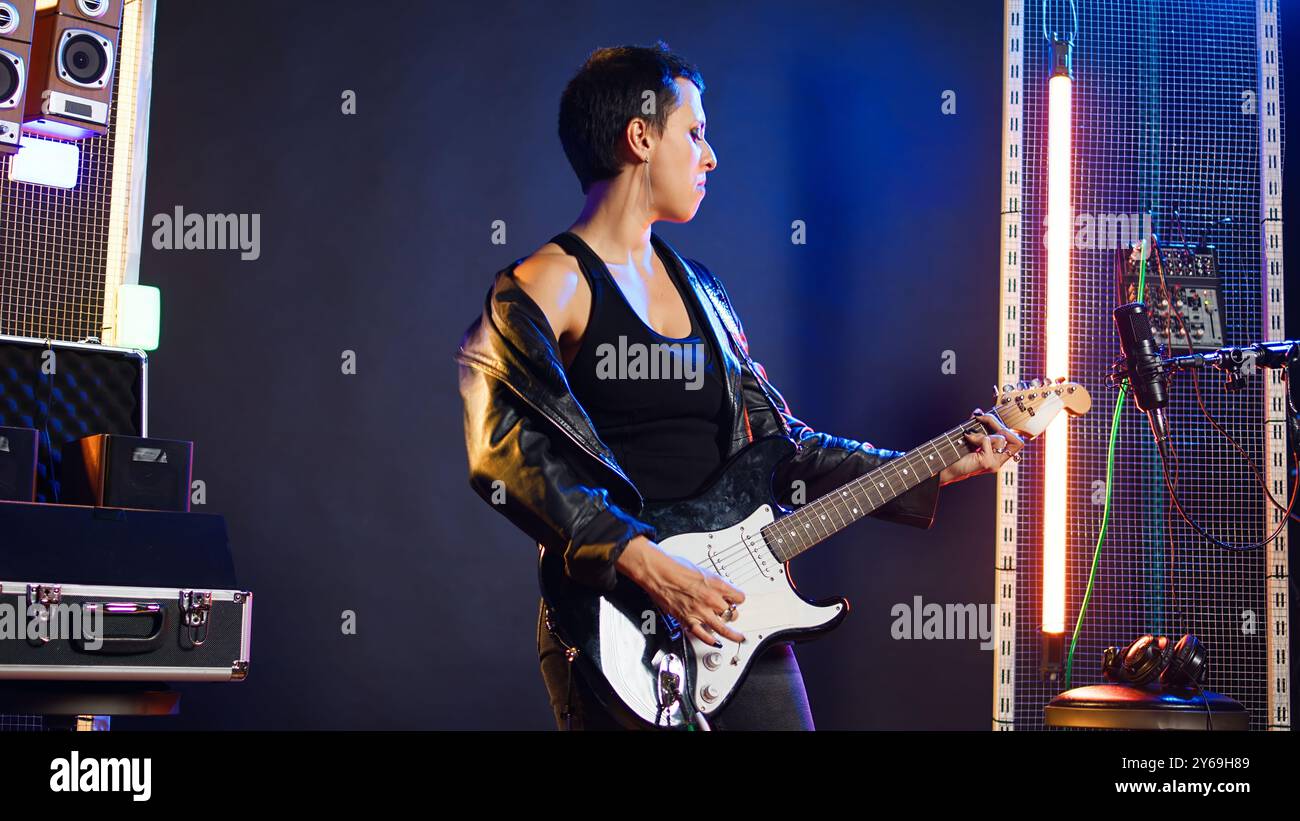 Woman performer showing thumbs up symbol and playing guitar, edgy ...