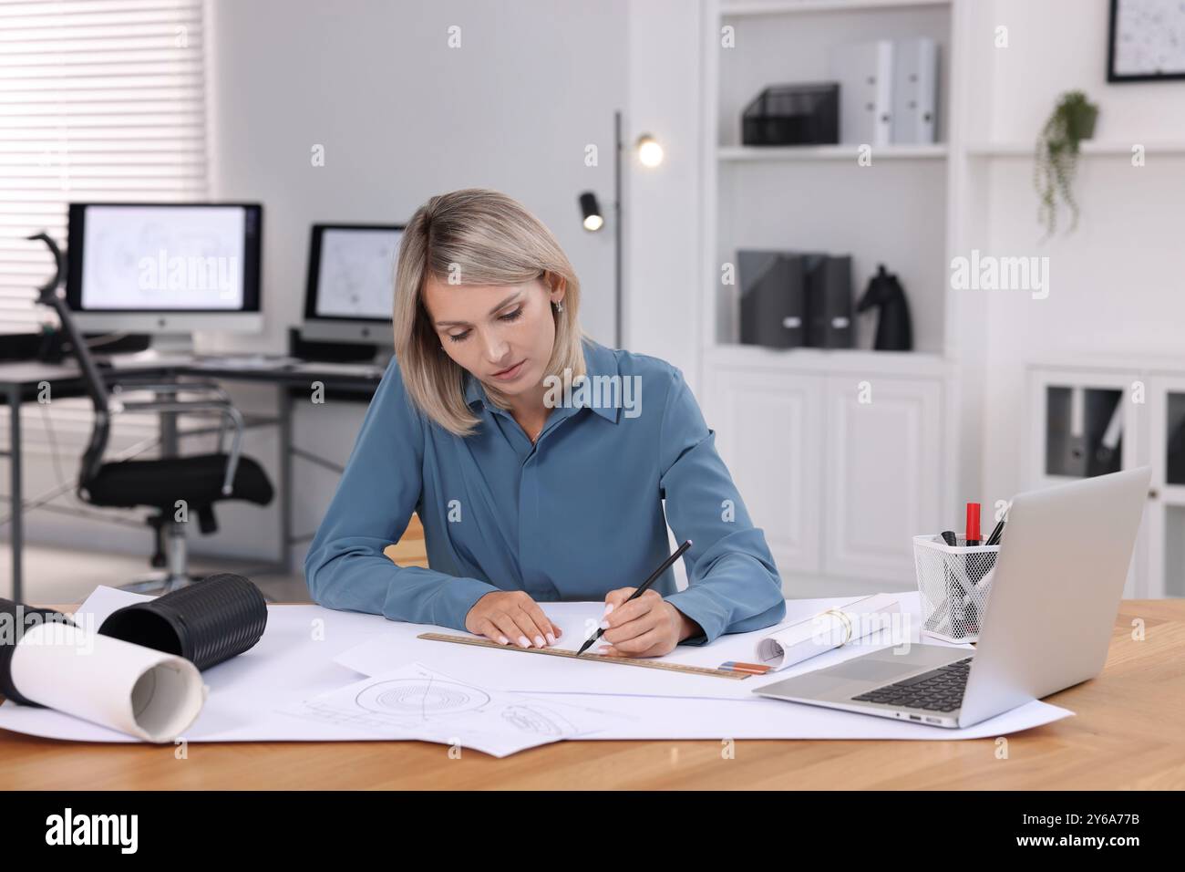 Architect making engineering drawing at table in office Stock Photo