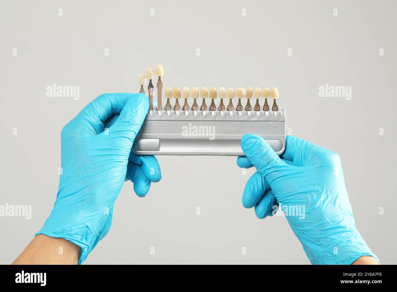 Doctor with teeth color chart on gray background, closeup. Dental veneers Stock Photo