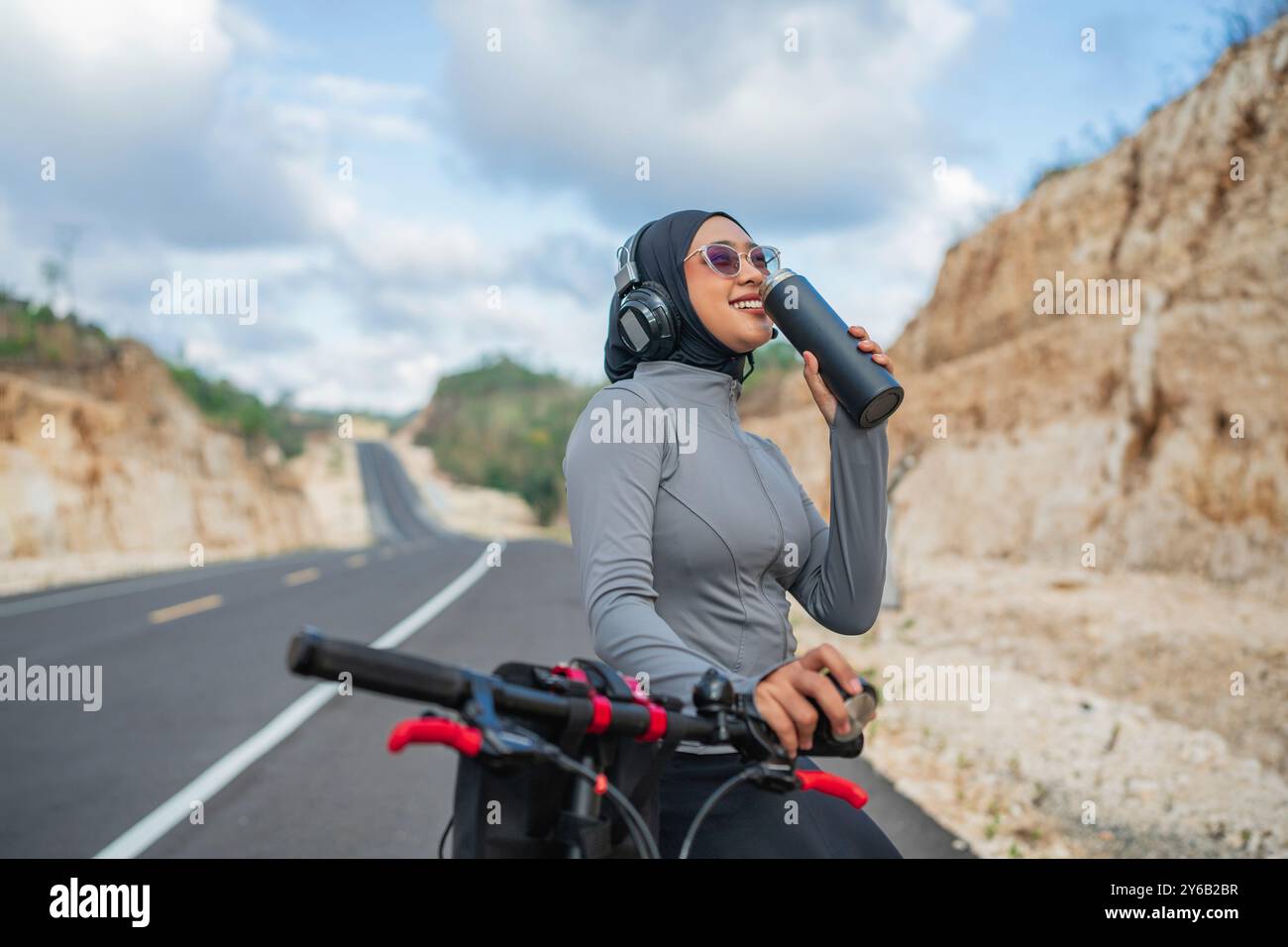 hijab woman enjoying drinking water when biking Stock Photo - Alamy