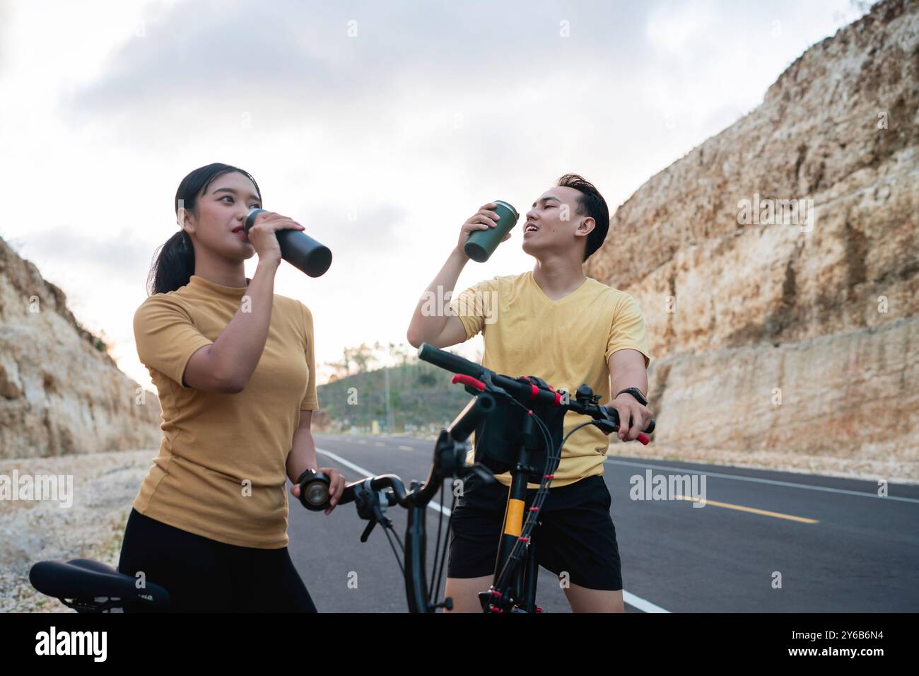 female and male biker taking rest and drinking water Stock Photo - Alamy