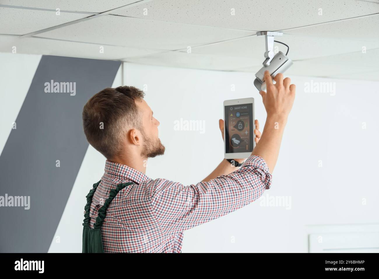 Male worker with tablet computer installing alarm system in room Stock Photo