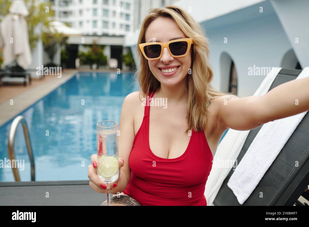Smiling Woman Holding Drink by Poolside Stock Photo