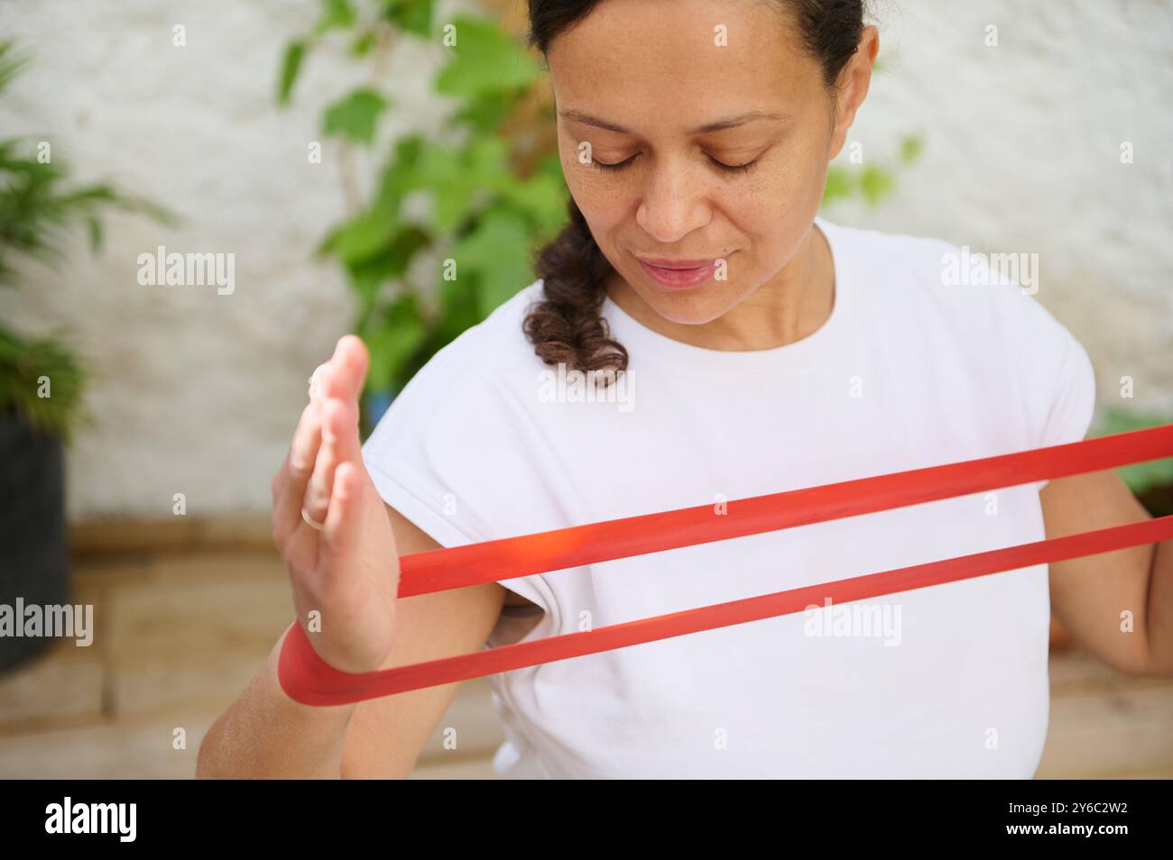 Woman using red resistance band outdoors, focused on fitness and ...