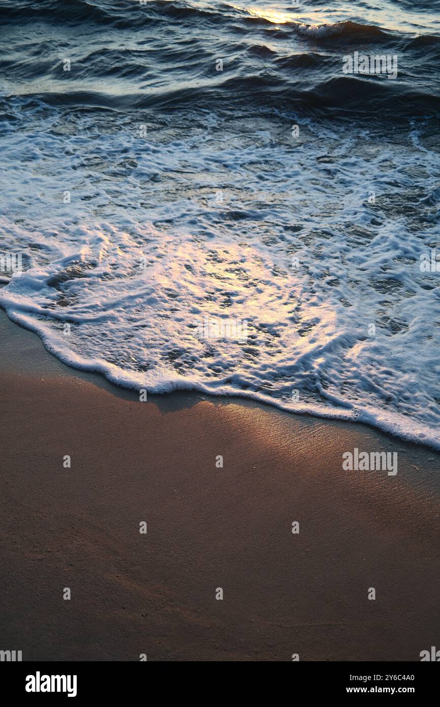 A serene view of ocean waves gently lapping onto a sandy beach during ...