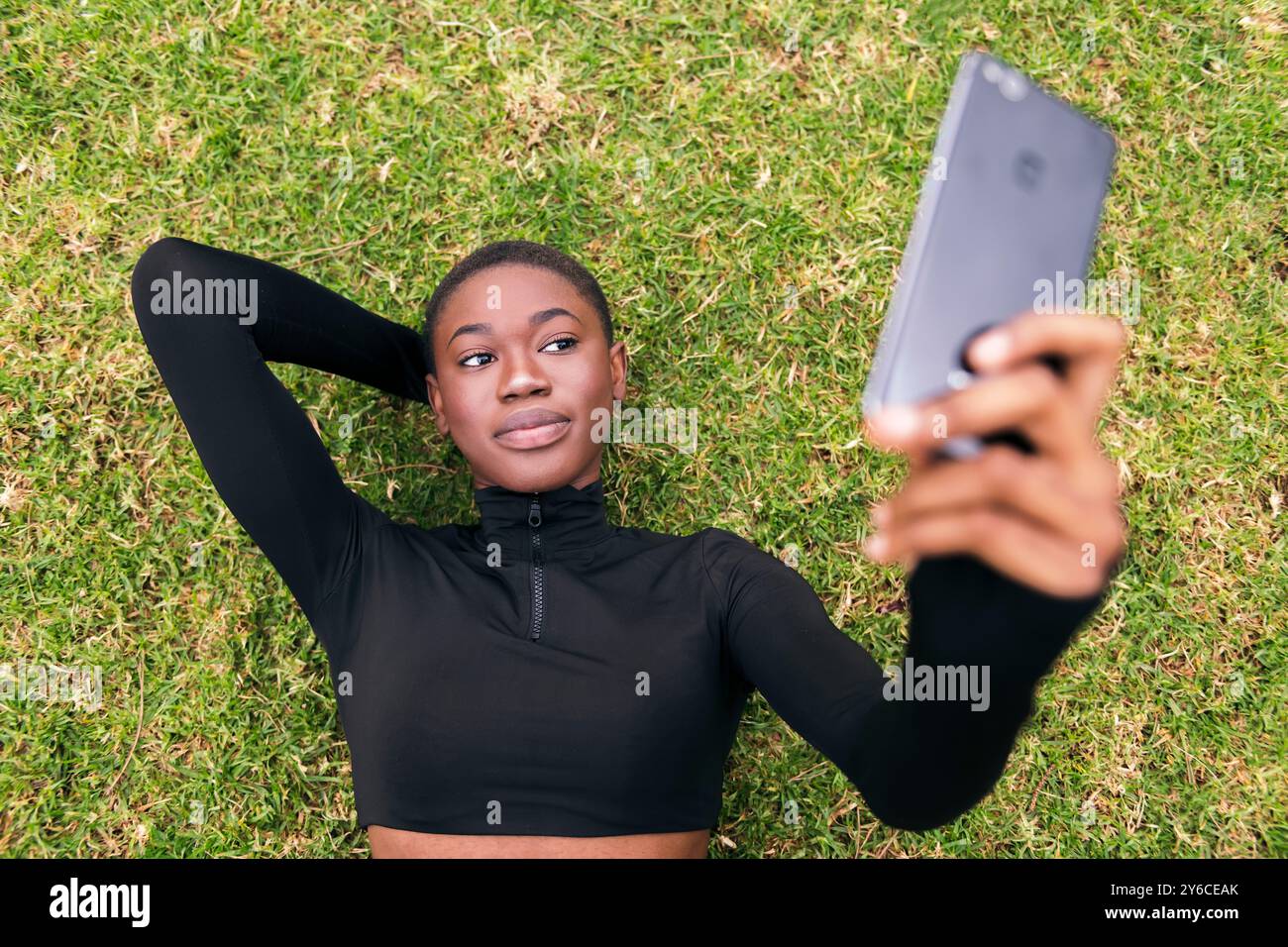 woman lying on the grass taking selfie on mobile Stock Photo