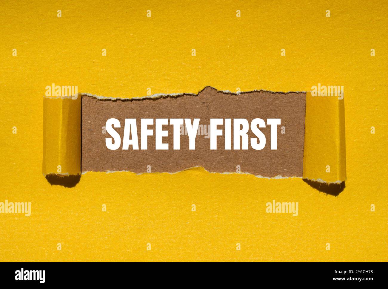 Safety first message written on ripped torn yellow paper with brown ...