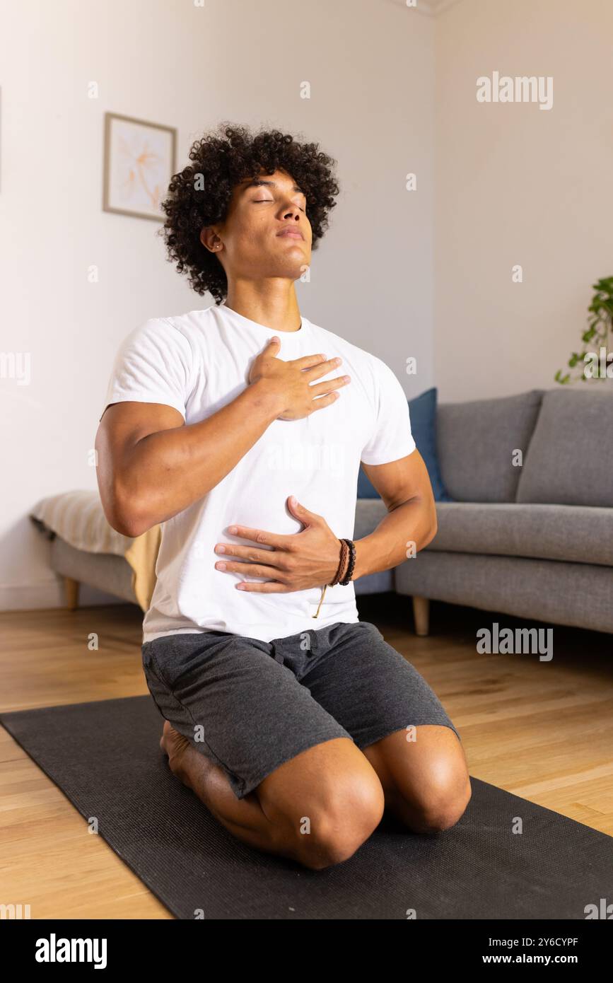 At home, Meditating on yoga mat, man practicing mindfulness and deep breathing exercises Stock Photo