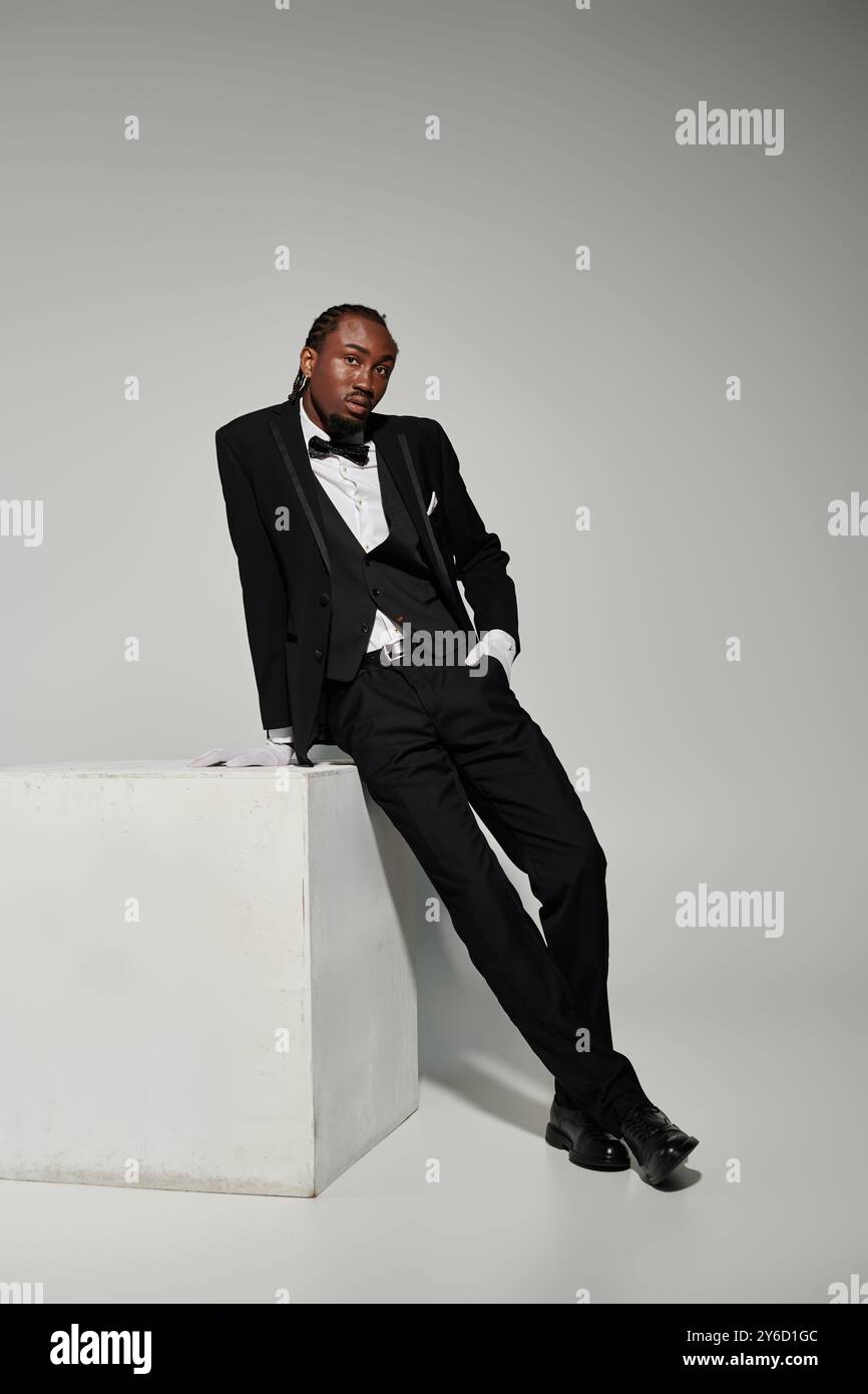 Dressed in a formal suit and vest, a young man exhibits elegance while ...