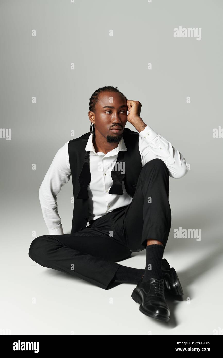 Dressed in a sharp suit, a young man reflects while seated casually on ...