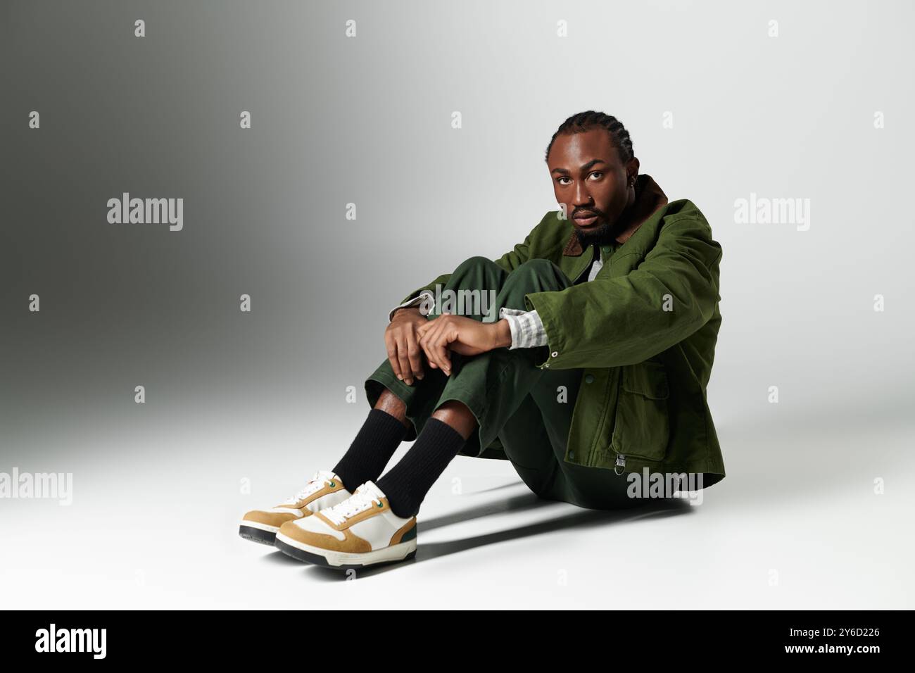 A young man poses elegantly in a vibrant green ensemble, radiating ...