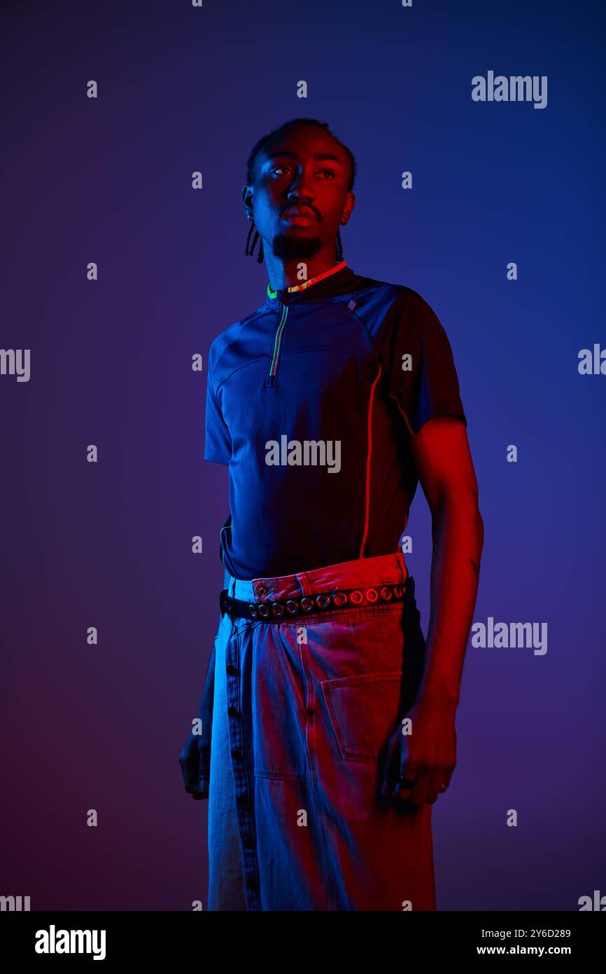 A young African American man showcases his stylish attire, illuminated ...