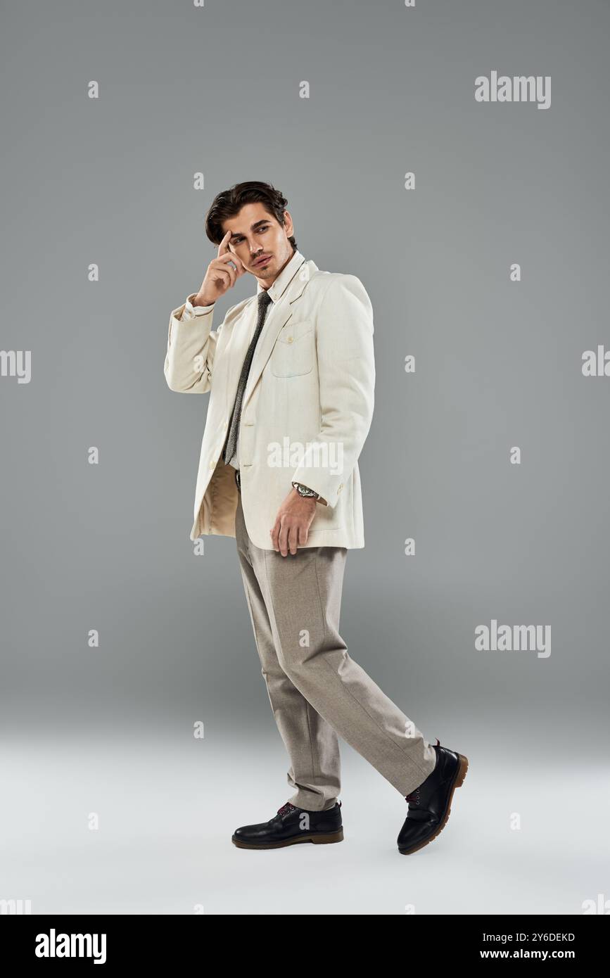 A young handsome man elegantly poses in a stylish suit, showcasing ...