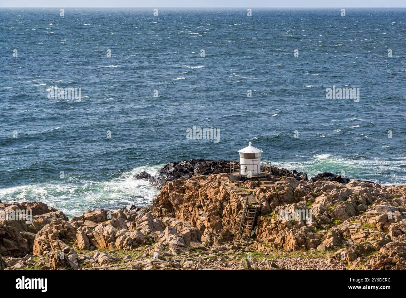 Small white lighthouse below Kullen lighthouse. Kullaberg a rocky region with steep cliffs and a height of up to 188 meters. At the tip of the Kullaberg peninsula stands the small Kullen Västra Lighthouse. Italienska vägen, Höganäs kommun, Skåne, Sweden Stock Photo