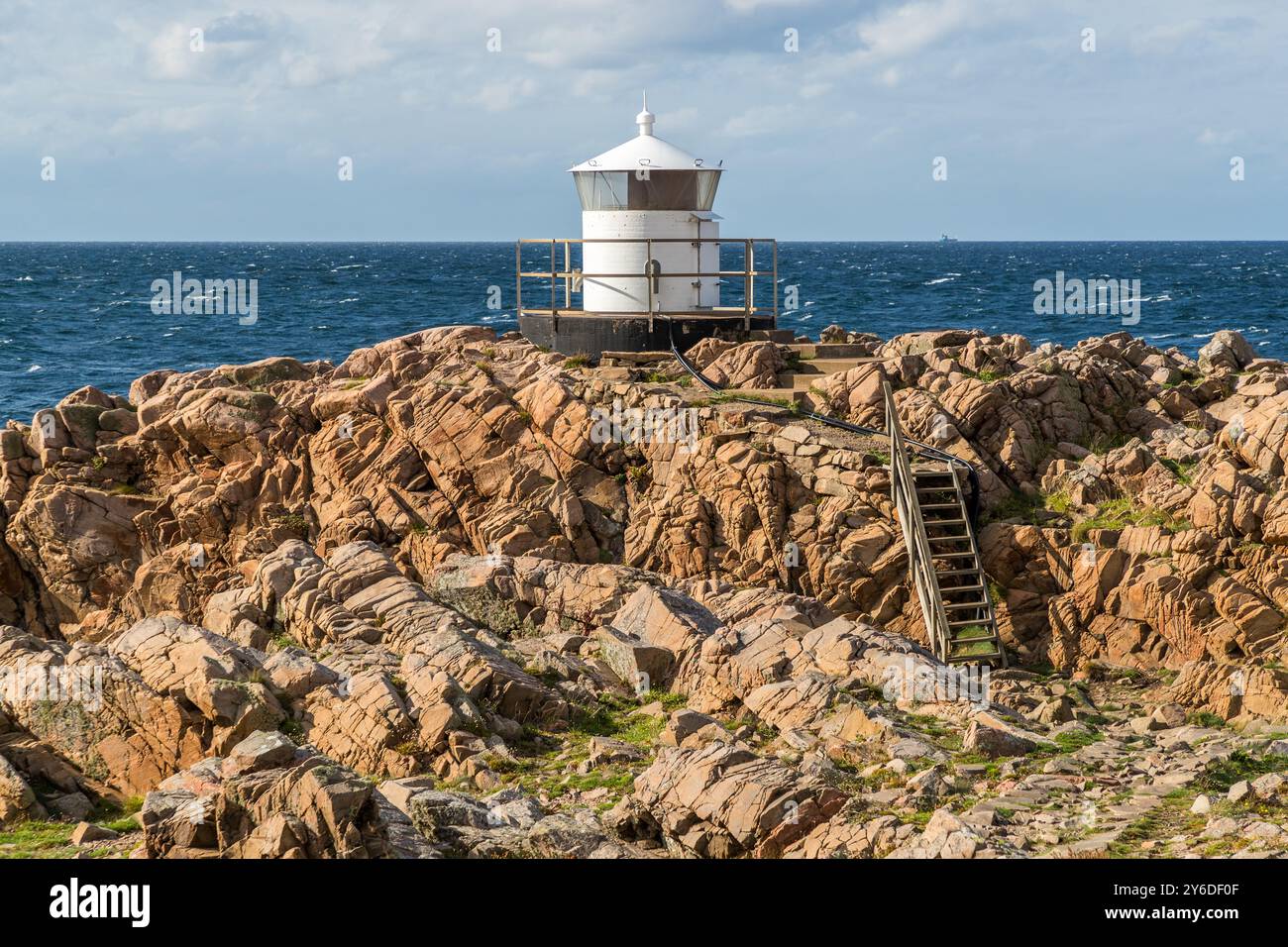 Small white lighthouse below Kullen lighthouse. Kullaberg a rocky region with steep cliffs and a height of up to 188 meters. At the tip of the Kullaberg peninsula stands the small Kullen Västra Lighthouse. Italienska vägen, Höganäs kommun, Skåne, Sweden Stock Photo