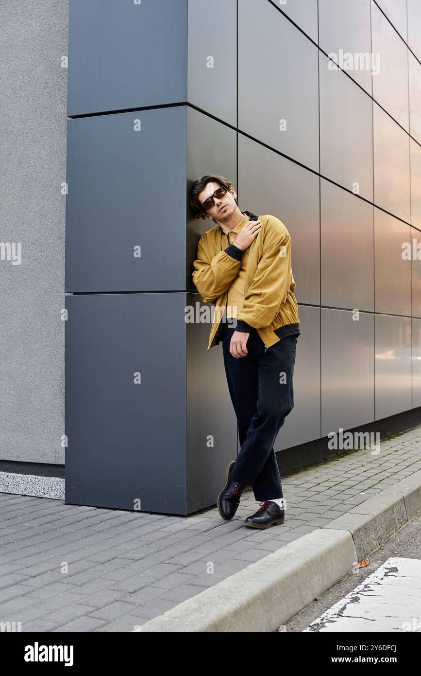 A trendy young man poses confidently in a fashionable autumn outfit by ...