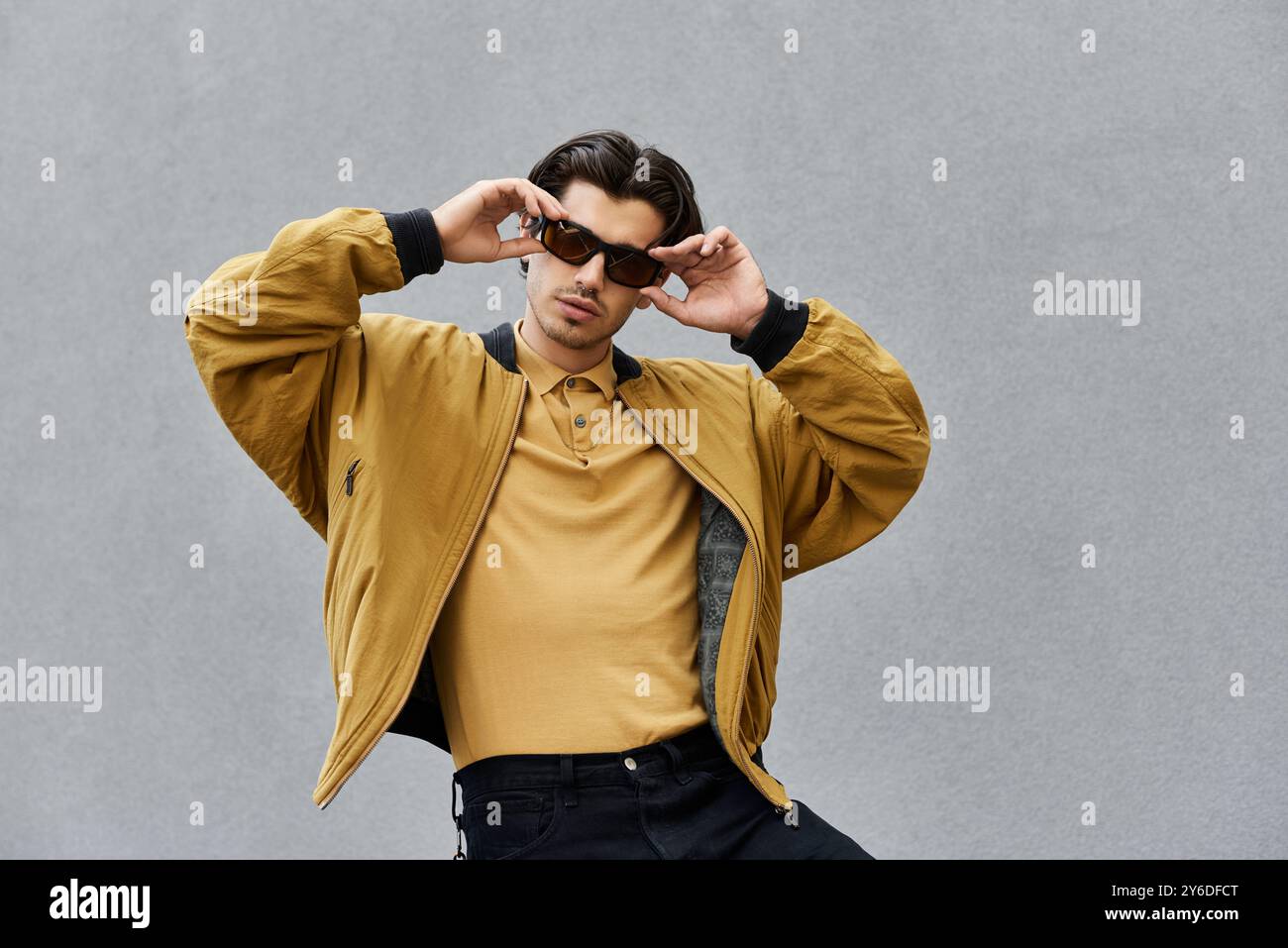 A young man confidently poses in a fashionable autumn outfit, radiating ...