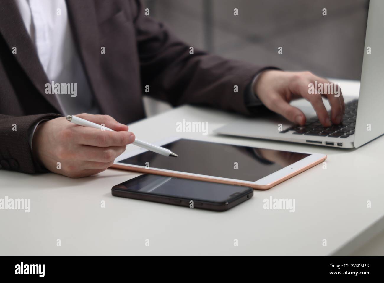 Businessman using different devices at white table indoors, closeup. Modern technology Stock Photo