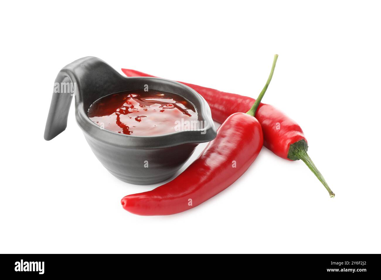 Hot chili sauce in gravy boat and peppers isolated on white Stock Photo