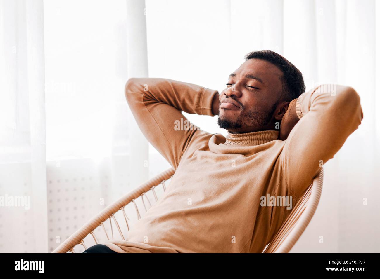 Black Guy Relaxing Sitting On Modern Chair Against Window Indoor Stock Photo