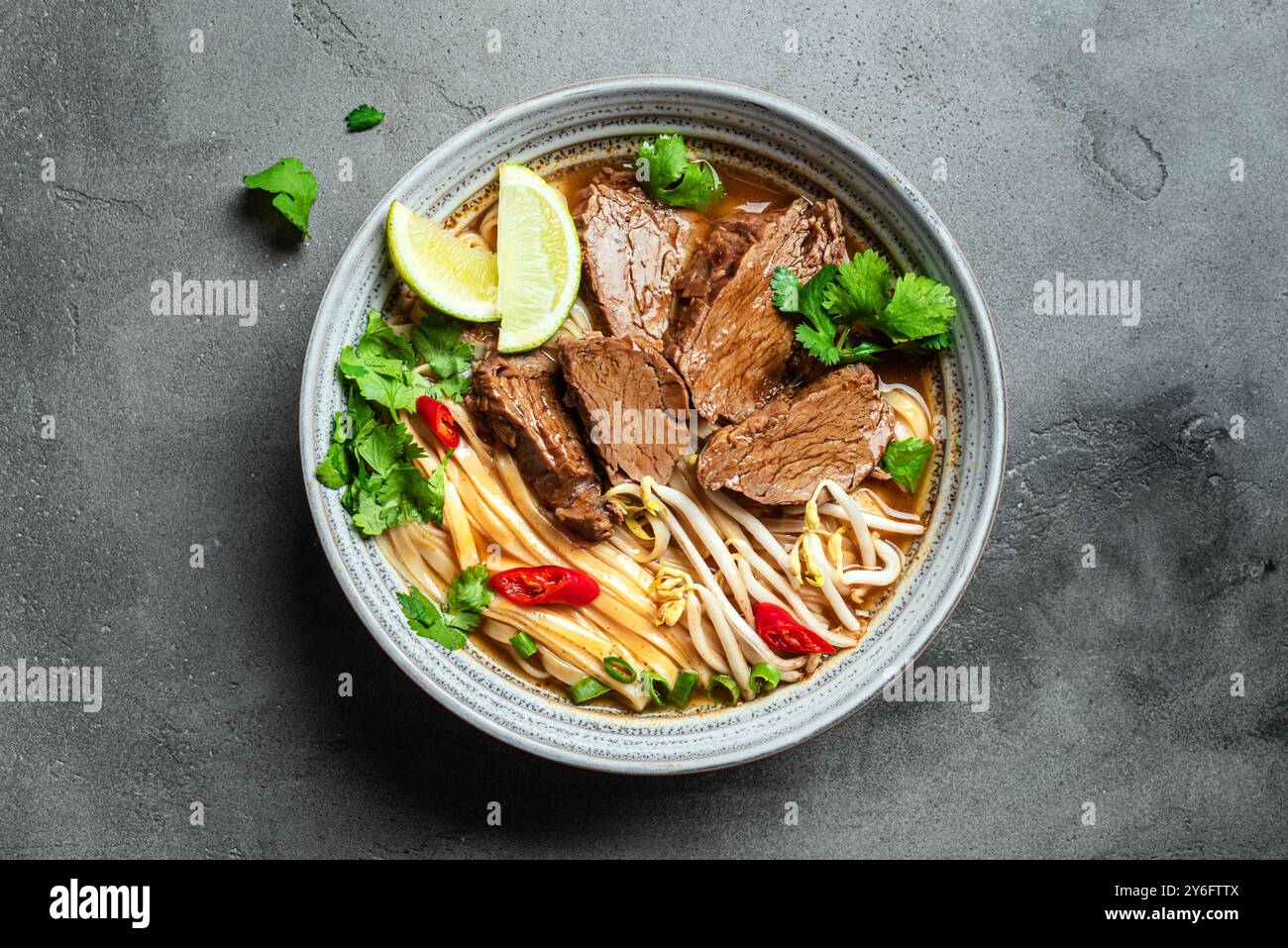 Pho Bo Vietnamese soup. Bowl of fresh delicious asian soup with rice noodle, beef meat, herbs, soy sprouts and chili, top view. Asian cuisine, comfort Stock Photo