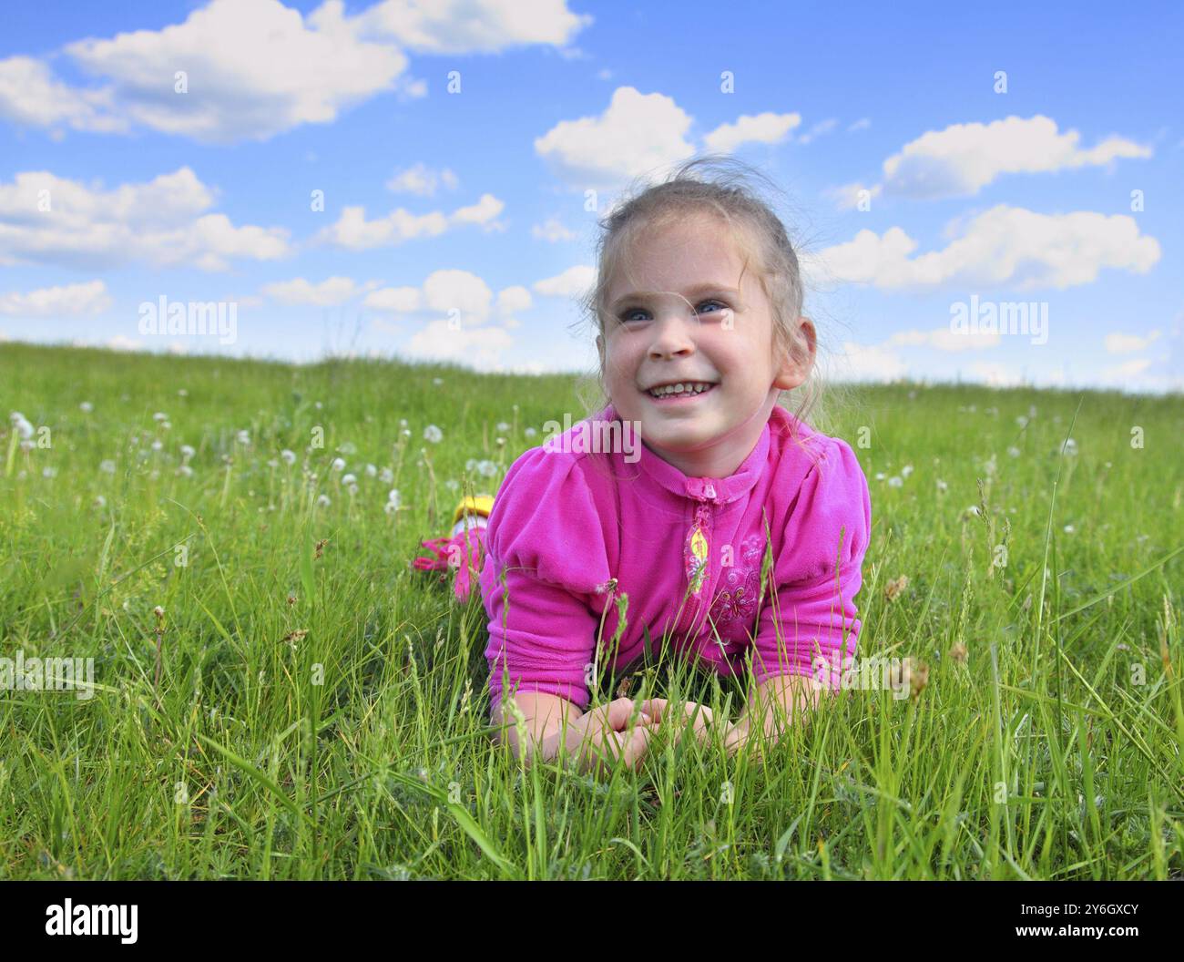 Happy smiling little girl lying on green grass Stock Photo - Alamy