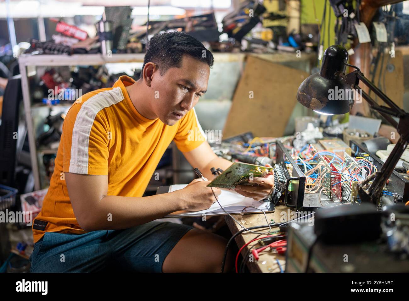repairman looking at a circuit while working at a workbench Stock Photo