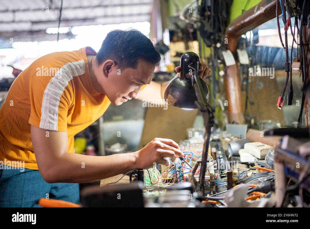 technician working on testing electronics using a screwdriver under the light Stock Photo