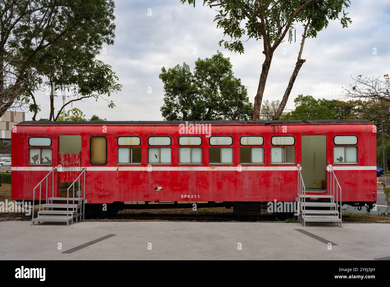 A red vintage train carriage converted into a stationary structure in an outdoor setting surrounded by trees. Stock Photo