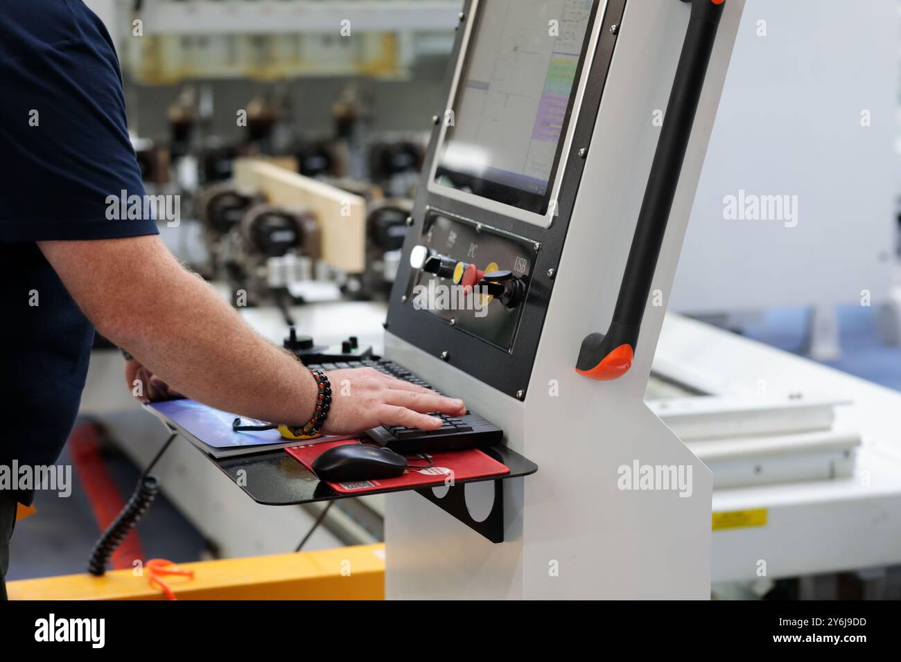Operator works at the control panel of the CAD/CAM (computer-aided design and computer-aided manufacturing) woodworking machine. Selective focus. Stock Photo