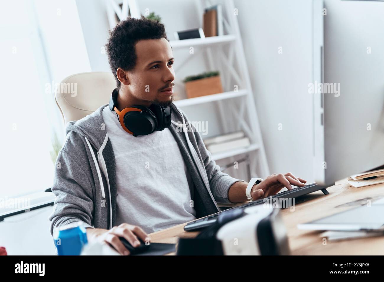 Computer hacker. Concentrated young man in casual clothing using computer while spending time at home Stock Photo