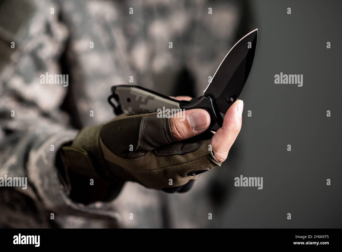 The man wearing tactical gloves using folding knife. Stock Photo