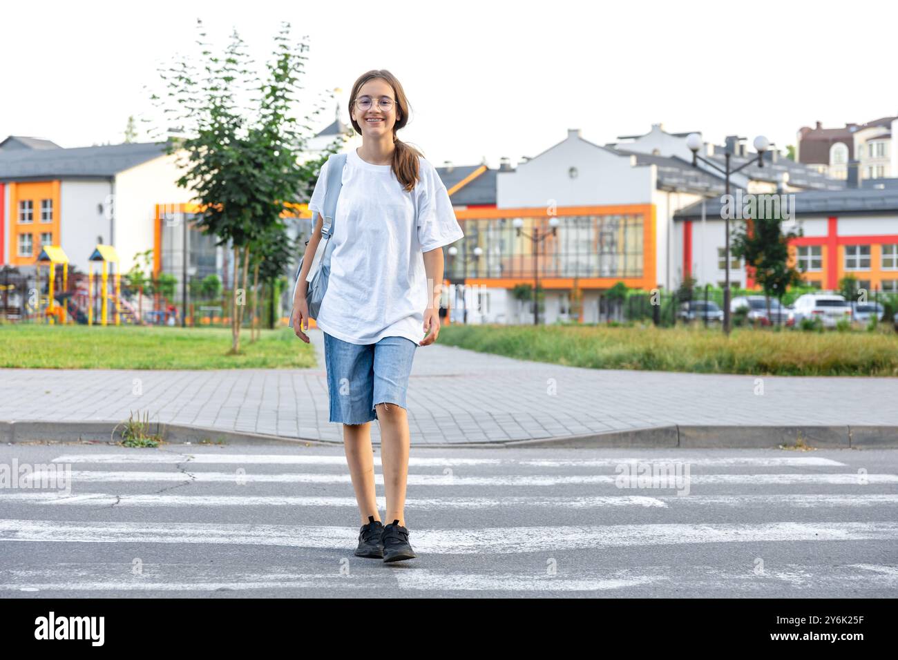 The girl goes to school. A schoolgirl crosses a pedestrian crossing ...
