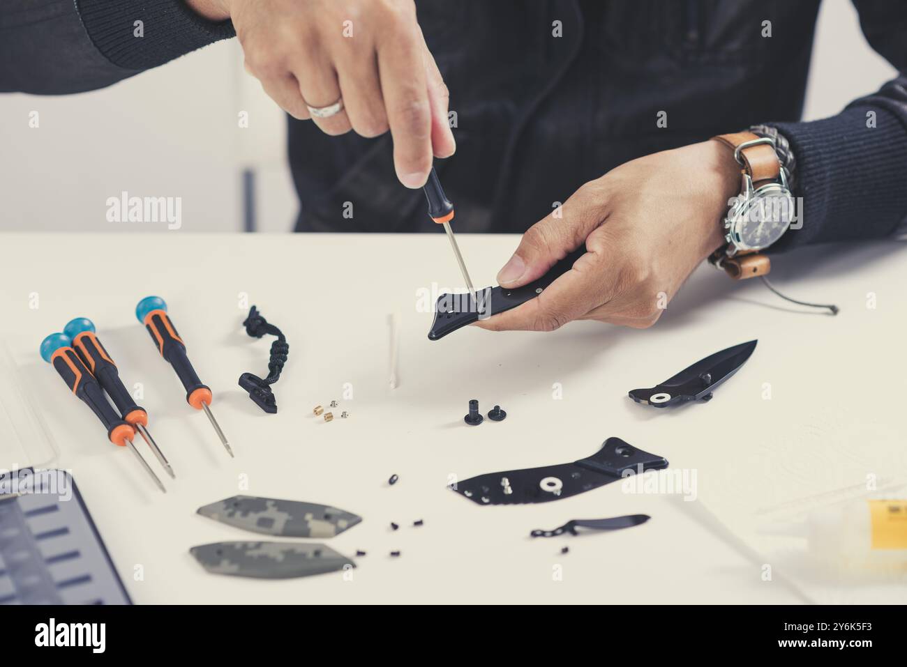 The man disassembles a pocket knife for cleaning. Pocket knife claening and maintenance concept. Stock Photo