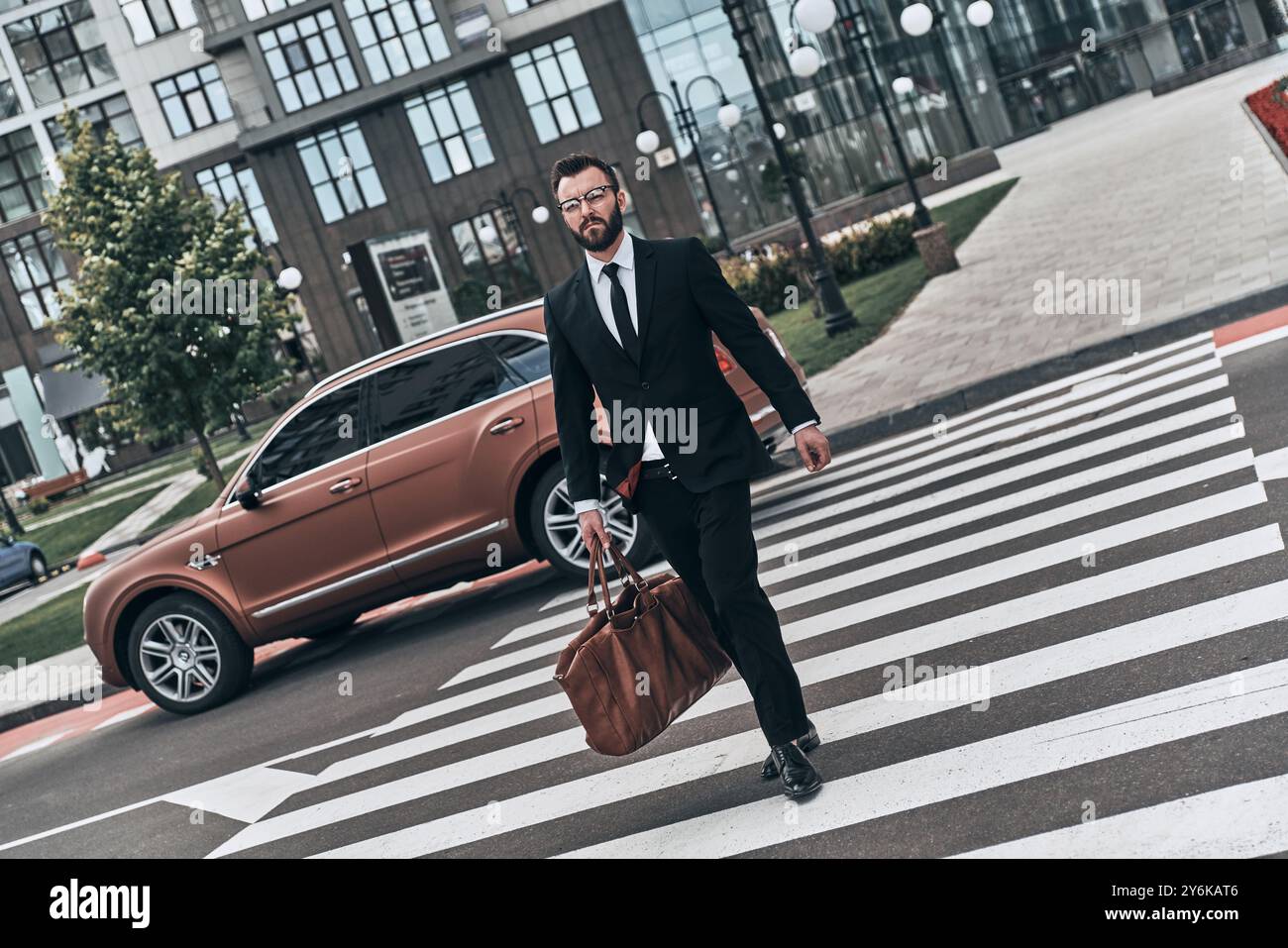 Young businessman. Full length of young man in full suit crossing the street while walking outdoors Stock Photo