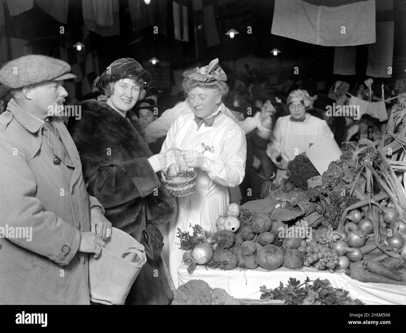 Bazaar at St Barnabas Hall, Southampton, in aid of the hostel for Mothers and Babies. Lady Montagu making a purchase from Lady Milner-White at her farm produce stall.  Lord Montagu is seen holding the bag.  3 December 1920 Stock Photo