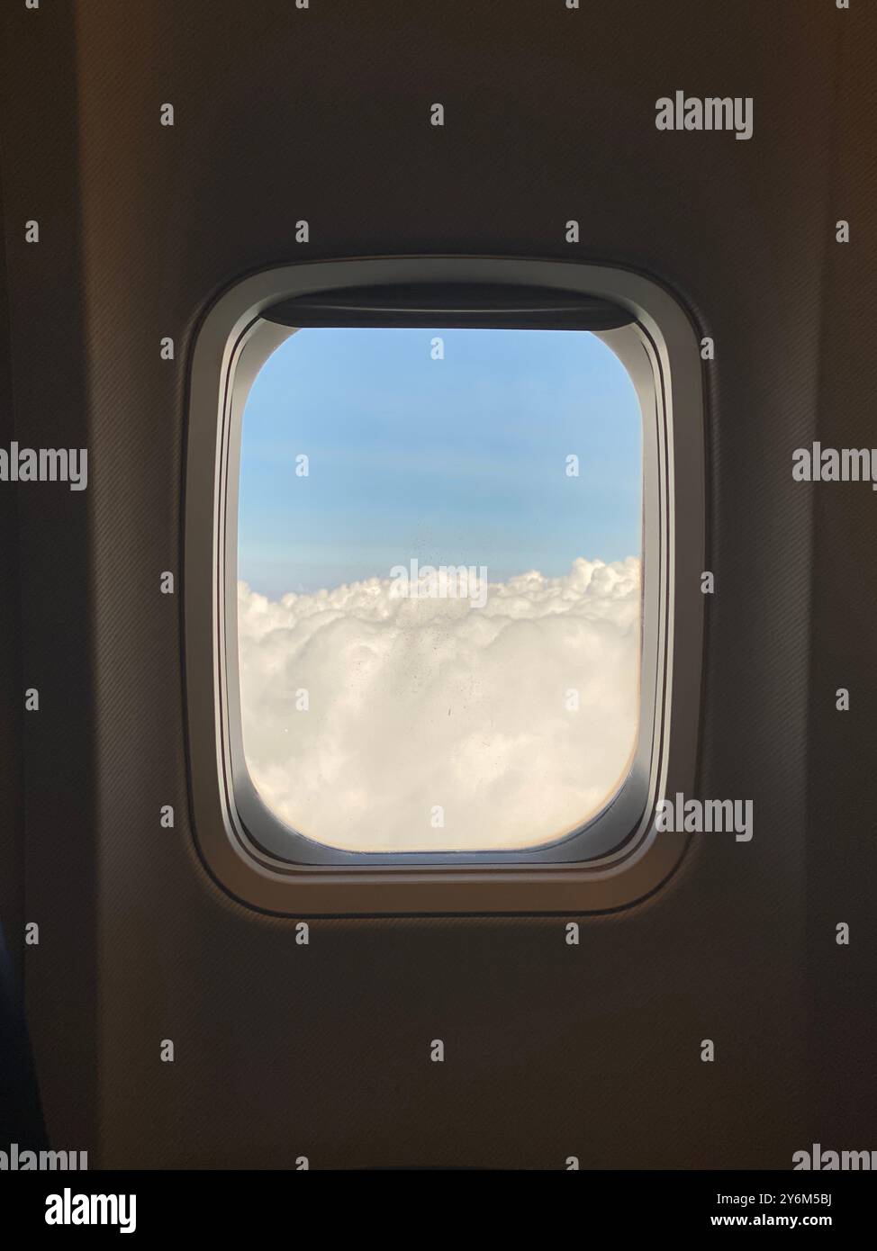 Fluffy clouds with a warm glow seen through an airplane window.' - Smartphone Captured Stock Image