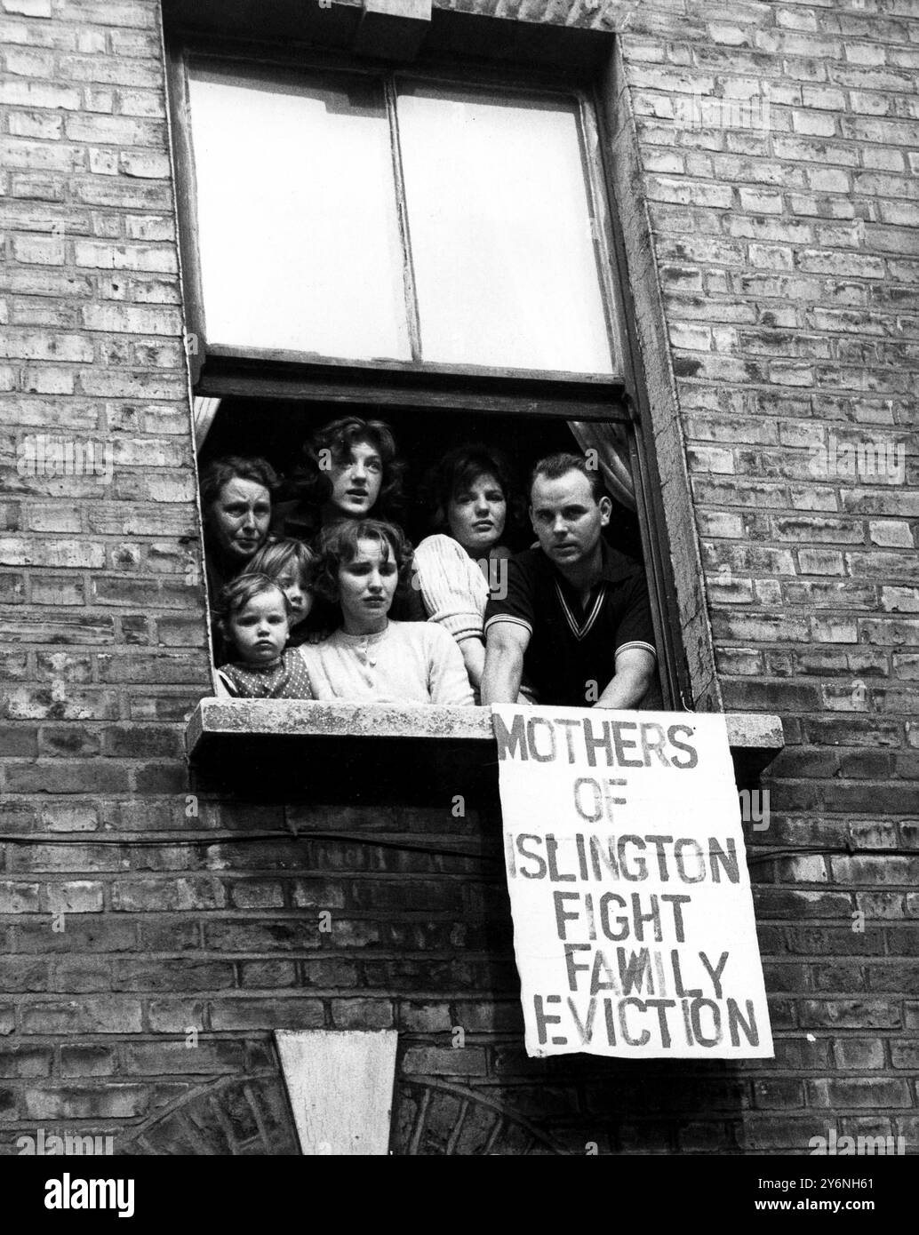 Mr McDonaugh and his wife with some of their children and friends looking from a first floor window of No 28 Athelstane Road, Finsbury Park, North London, when they were reported to be barricaded in to escape eviction.  September 21st 1961 Stock Photo