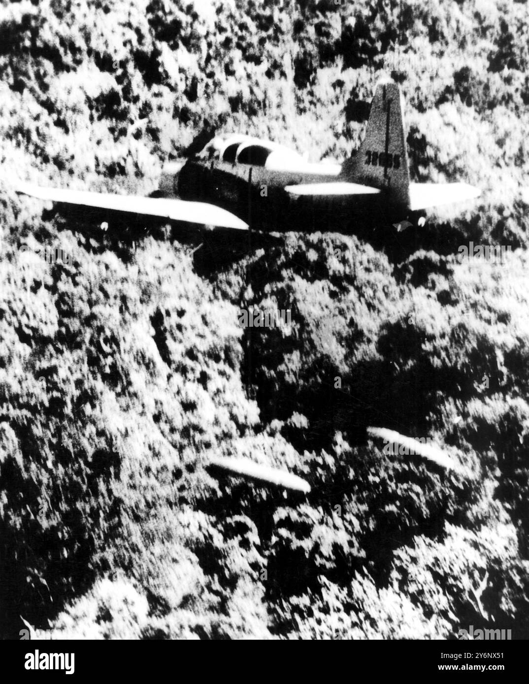 Vietnamese A-IE skyraider fighter-bomber is pictured dropping napalm bombs above the dense jungle foliage of Vietnam to destroy well-concealed enemy forces.  Napalm can penetrate thick jungle foliage and destroy the target underneath. 4th April 1965 Stock Photo