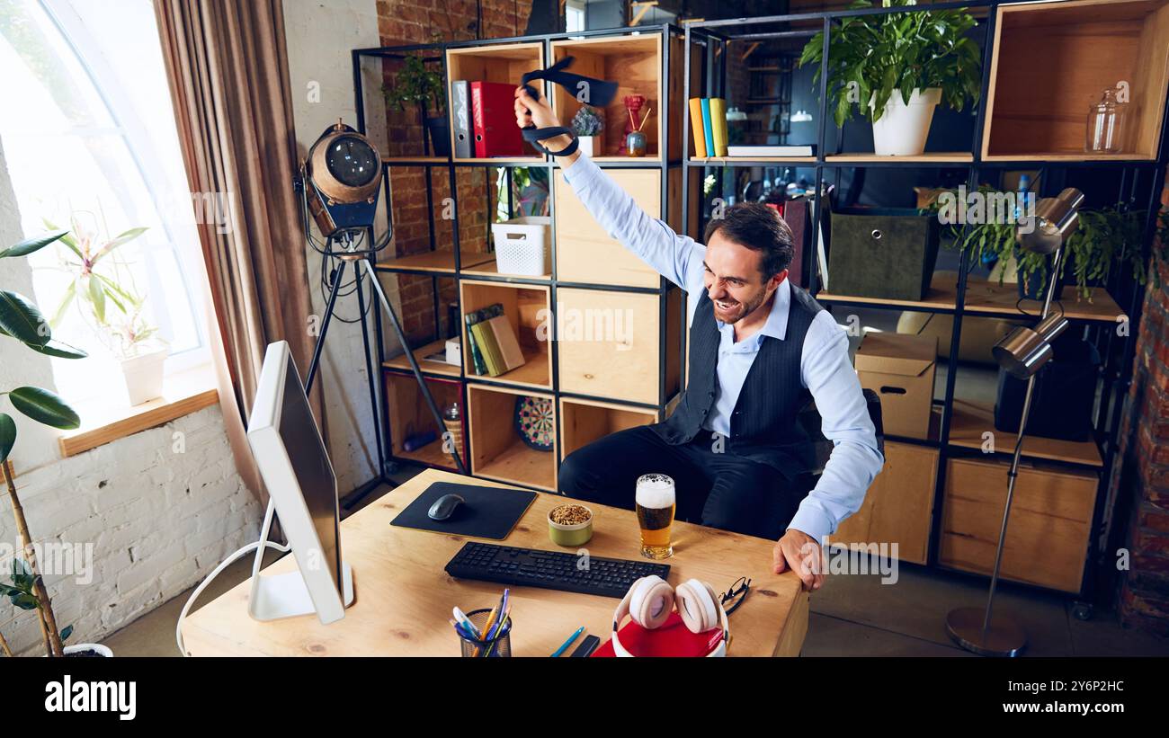 Triumphant and full of energy, businessman raises his tie in ...