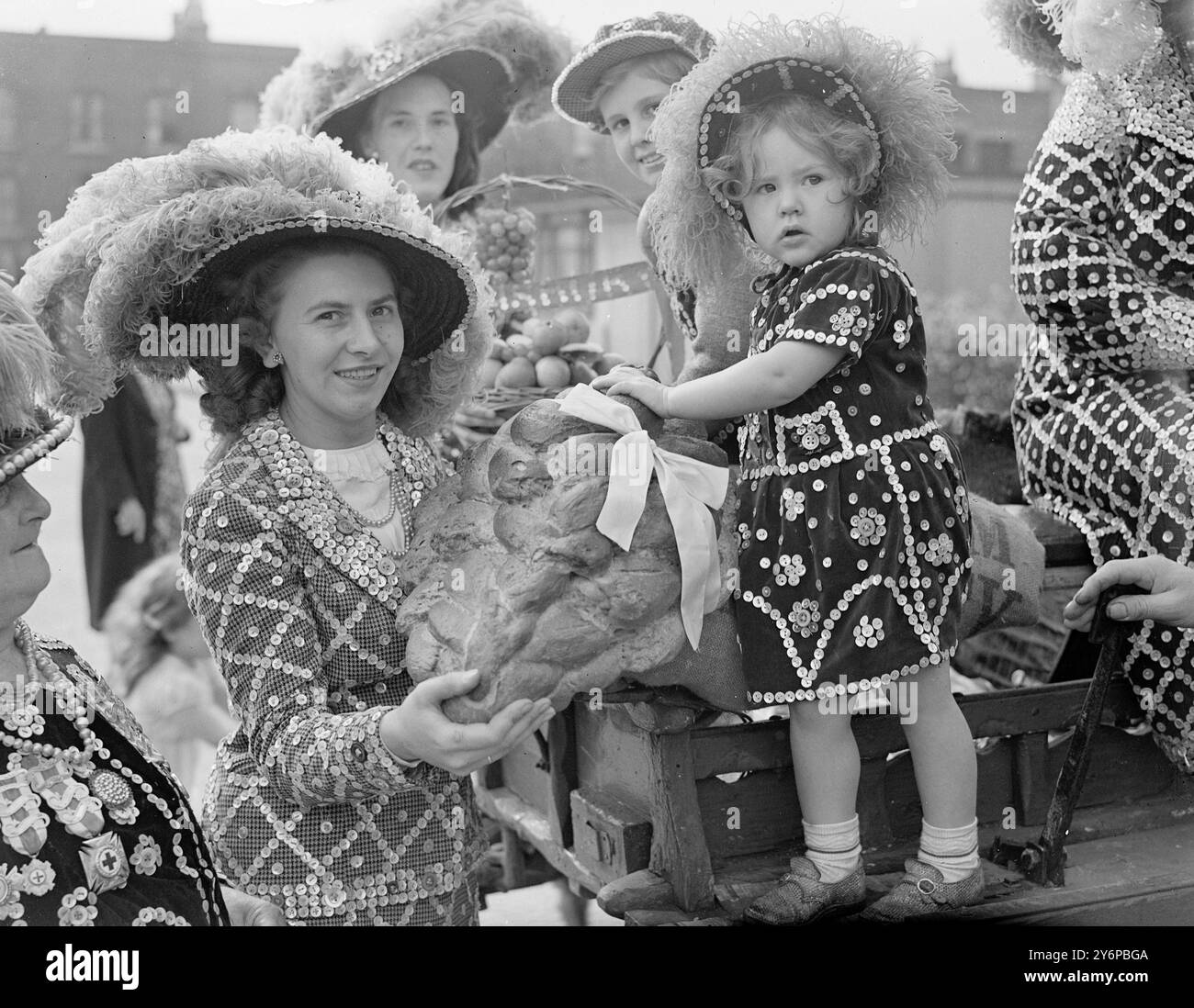 ' ROYAL ' LOAF AT PEARLIES 'HARVEST FESTIVAL'S    Wearing their full regalia , London's pearly' Kings ' and their families attended the Costermongers ' harvest festival service at the ' costers' Cathedral '-St Mary Magdalene Church, Southwark.  (The pearly' Royal family's', the clothing decorated with thousands of pearl buttons, Is traditionally associated with the coster life of Hackney London. They are active workers of the charitable causes).    PICTURE SHOWS:-This Marie Louise Marriott, pearly Princess' of Finsbury, and her niece JEAN MARRIOTT, aged 2 1/2, arrived with a loaf of bread for Stock Photo