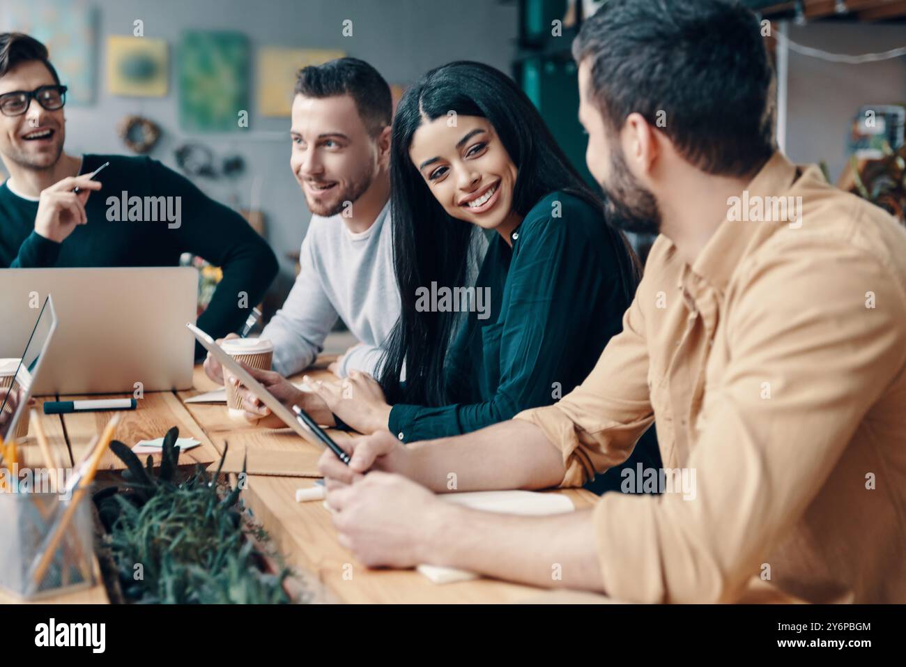 Business is not boring. Group of young modern people in smart casual wear discussing something and smiling while working in the creative office Stock Photo