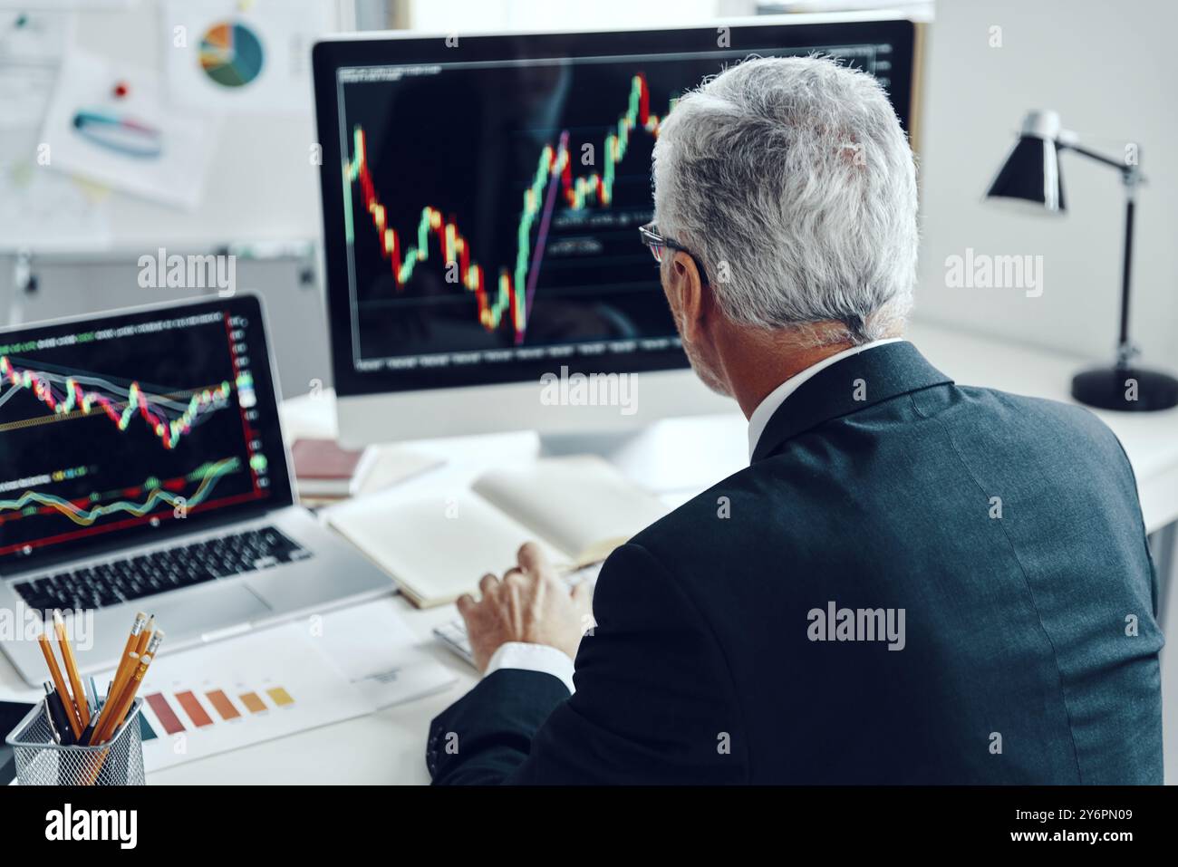 Top rear view of senior trader in elegant business suit using computer while working at the office Stock Photo