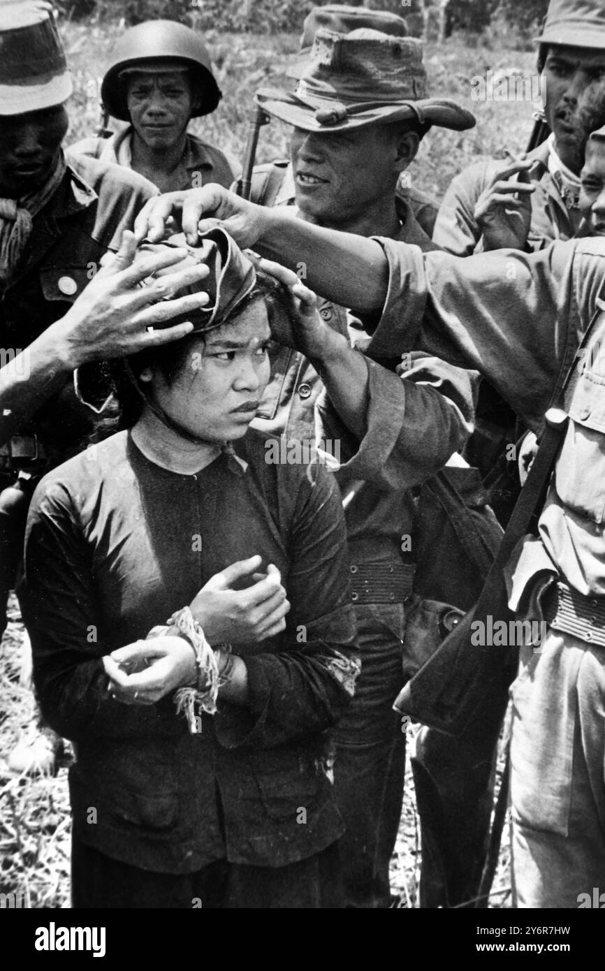 10 MAY 1962 SOUTH VIETNAM SOLDIERS BULLY A GIRL ACCUSED OF SPYING FOR THE NORTH COMMUNIST GUERILLAS BY PLACING A RED CAP ON HER HEAD. TRUONG HOA, VIETNAM. Stock Photo