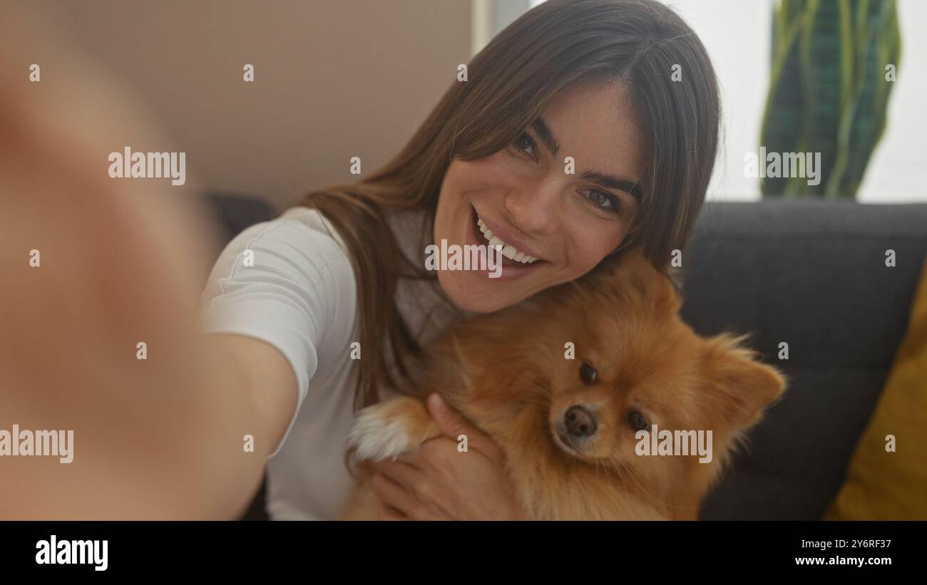 Smiling young woman takes a selfie with her adorable pomeranian dog in ...
