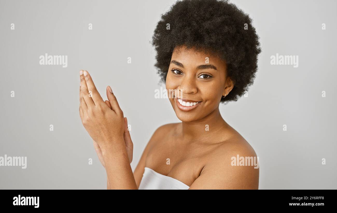 A cheerful african american woman with curly hair poses against a white ...