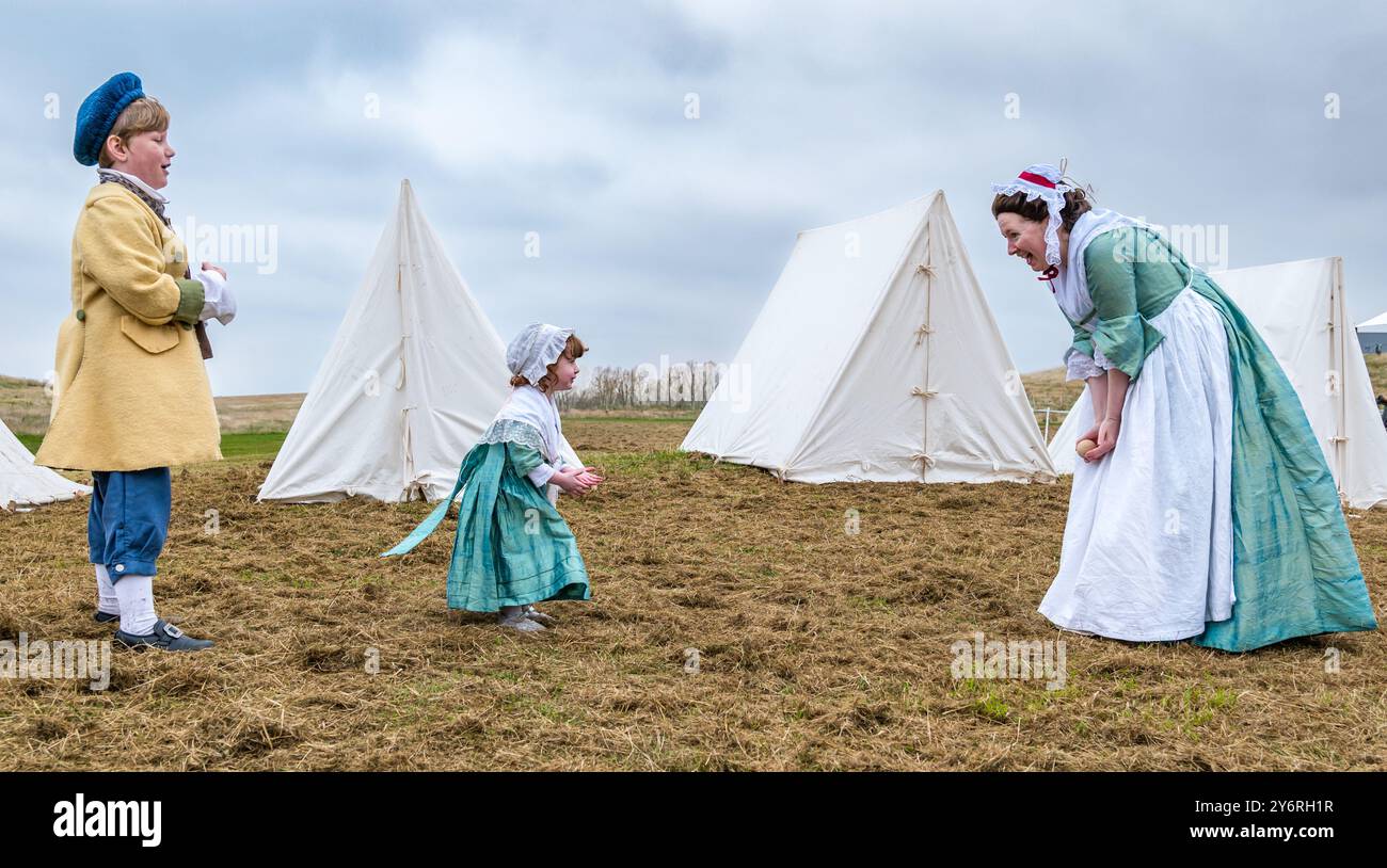 Mother and children in 18th century costume playing catch ball in Hanoverian camp, in Battle of Prestonpans re-enactment, East Lothian, Scotland, UK Stock Photo